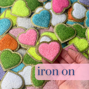 a hand holding a heart shaped iron on patch