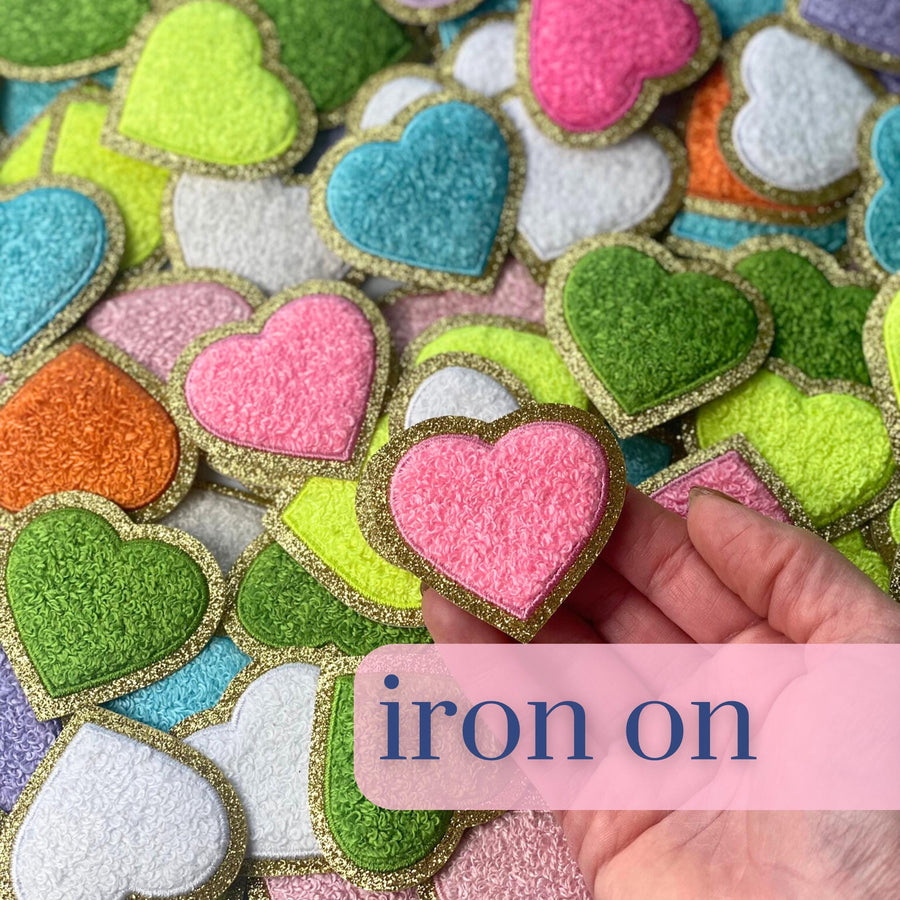 a hand holding a heart shaped iron on patch